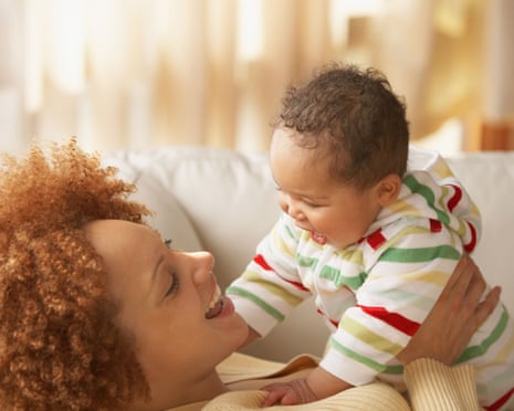 Mother and baby smiling at each other on sofa