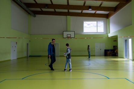 A man in a sports hall with a boy and a girl in their early teens