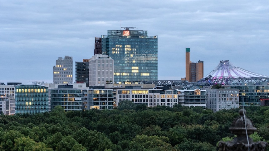 Several large buildings, seen from a distance. Trees are also visible in the foreground.