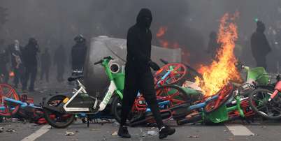 Um manifestante mascarado passa por bicicletas em chamas durante confrontos em uma rua de Paris, em meio a um dia de manifesta&ccedil;&otilde;es contra o custo de vida e o aumento dos pre&ccedil;os dos combust&iacute;veis, na Fran&ccedil;a, em 17 de outubro de 2026. Foto: REUTERS - Jack Taylor / RFI
