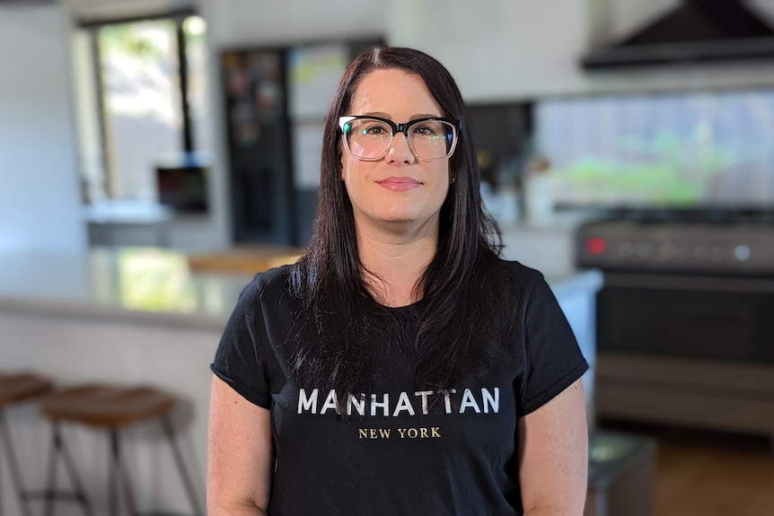 A young white woman with long dark hair standing in a kitchen