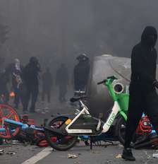 Um manifestante mascarado passa por bicicletas em chamas durante confrontos em uma rua de Paris, em meio a um dia de manifestações contra o custo de vida e o aumento dos preços dos combustíveis, na França, em 17 de outubro de 2026. Foto: REUTERS - Jack Taylor / RFI